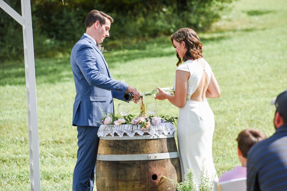 Wedding Look Book at Mountain Run Winery: Bride and groom pouring wine into a decanter during the ceremony 