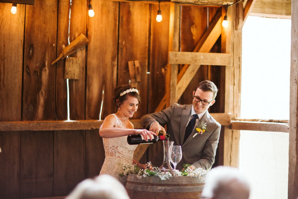 Wedding Look Book at Mountain Run Winery: Couple pours unity wine during ceremony in barn